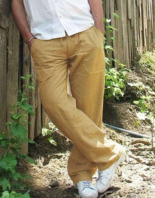 Load image into Gallery viewer, Man wearing khaki cotton linen trousers, casual style, leaning against a wooden fence in a natural outdoor setting.
